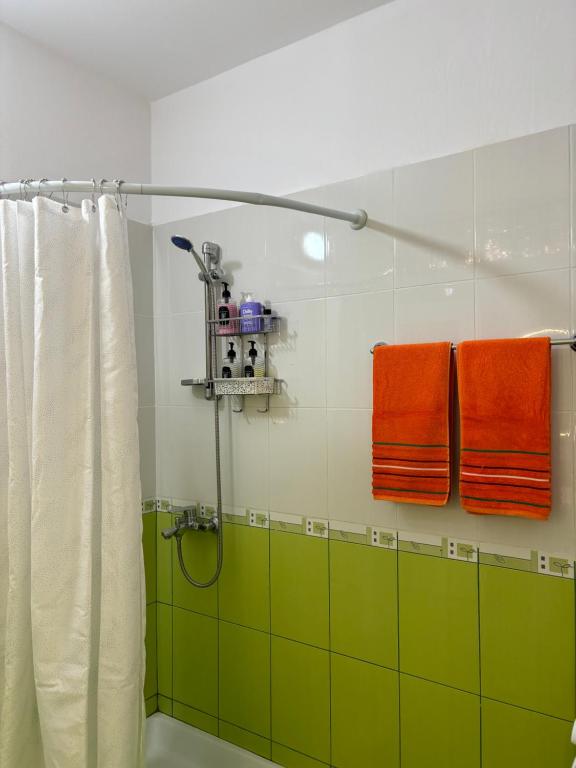 y baño con ducha y toallas verdes y naranjas. en Ralph Apartments, en Vlorë