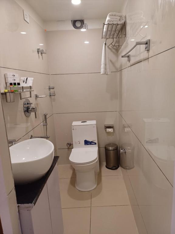 a white bathroom with a toilet and a sink at Accom Hotel in Ilām