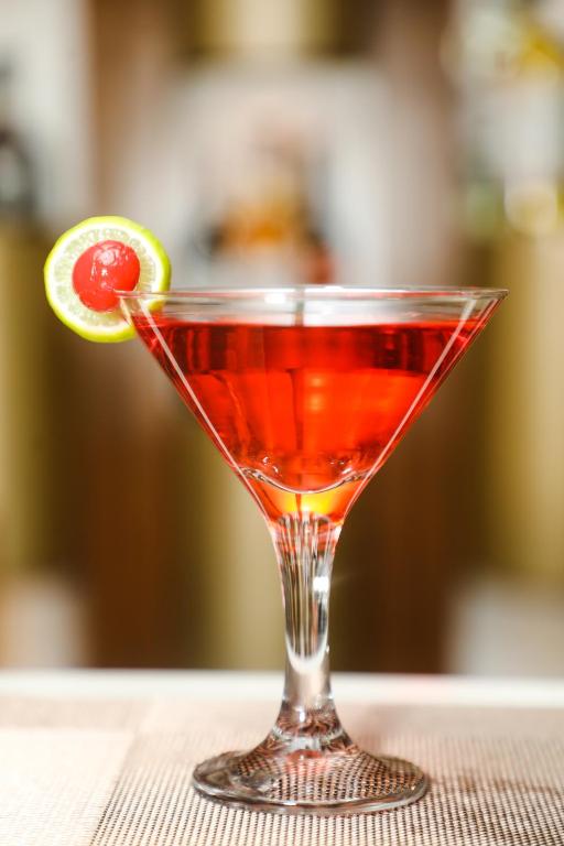 a red drink in a martini glass with a lime at Accom Hotel in Ilām