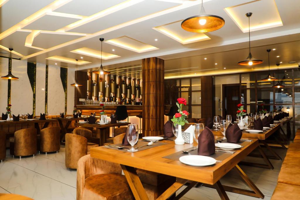 a restaurant with wooden tables and chairs and a bar at Accom Hotel in Ilām