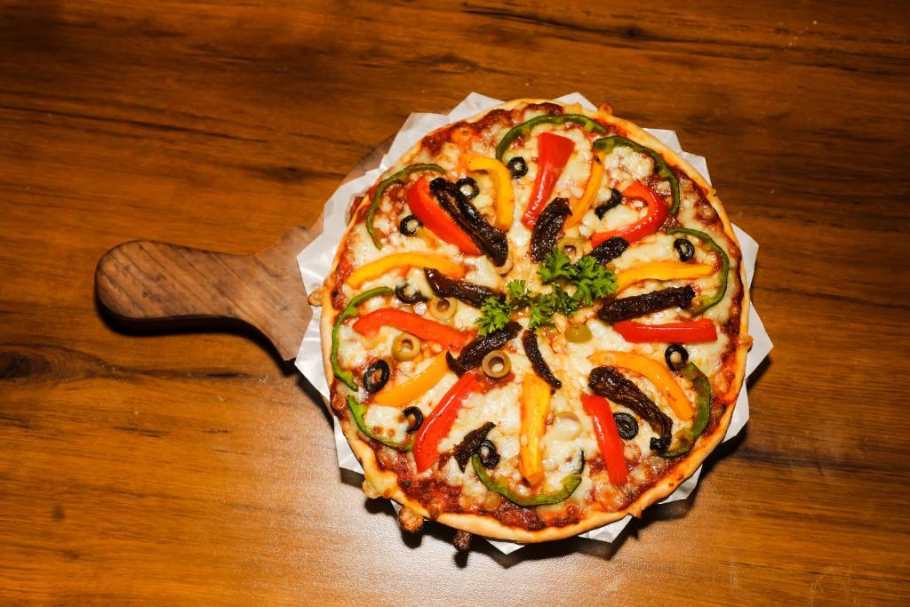 a pizza sitting on top of a wooden table at Accom Hotel in Ilām