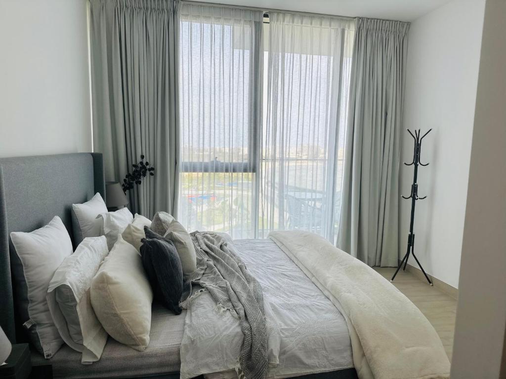 a bedroom with a bed with pillows and a window at Modern Sanctuary W/ Pool & Gym access in Sharjah
