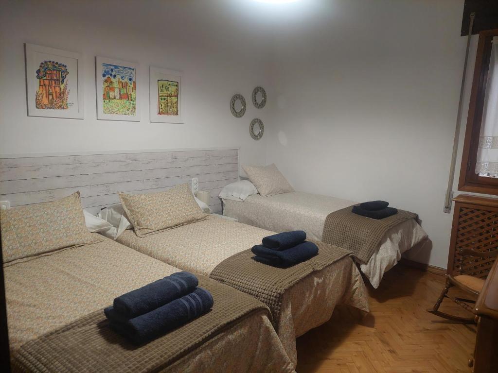 Tres camas en una habitación con almohadas azules. en La Tioca, en Cuenca