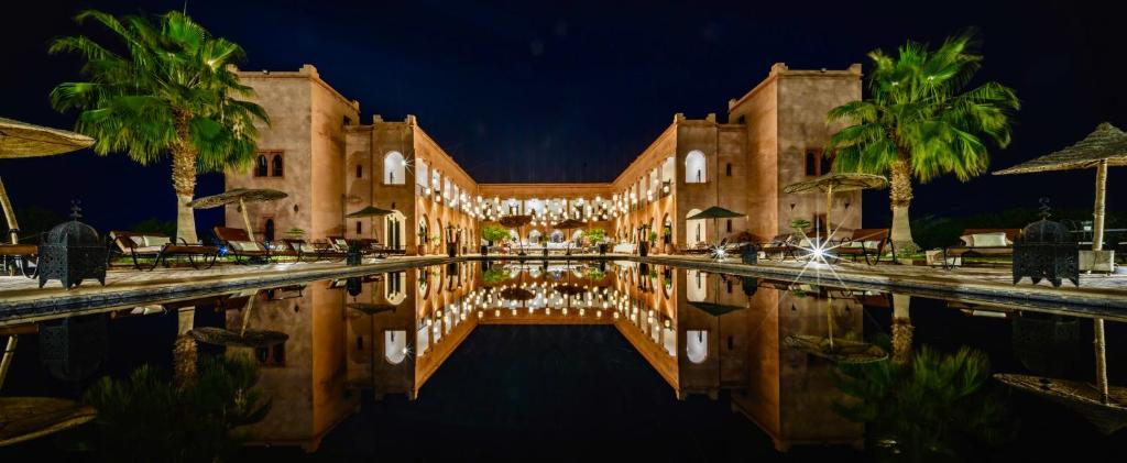 a building with a swimming pool at night at Kasbah Caracalla in Aït Zat