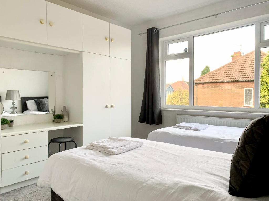 a white bedroom with two beds and a window at Immaculate 3-Bed Travel nest unavailable in Manchester