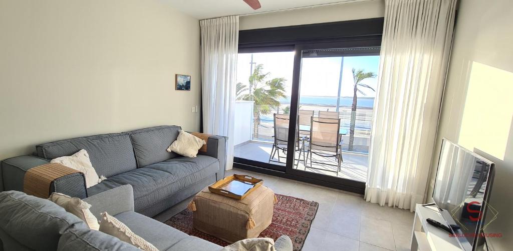 a living room with a couch and a view of the ocean at Arenas de Doñana amplio apartamento frente del mar in Sanlúcar de Barrameda
