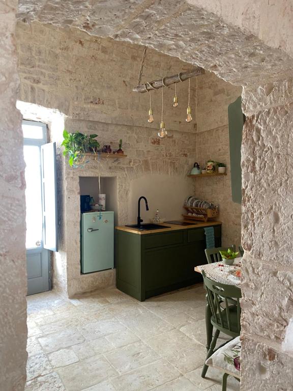 Il comprend une cuisine équipée d'un réfrigérateur vert et d'une table. dans l'établissement La Casetta, à Alberobello