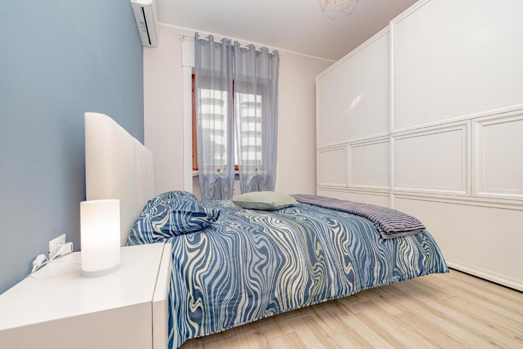 een slaapkamer met een bed met een blauw en wit dekbed bij SweetHomeSaronno-A 20 minuti da Milano in Saronno
