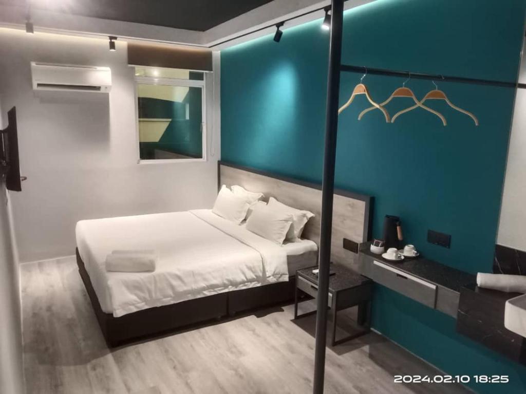 a bedroom with a white bed and a blue wall at Pantai Inn Kota Kinabalu in Kota Kinabalu