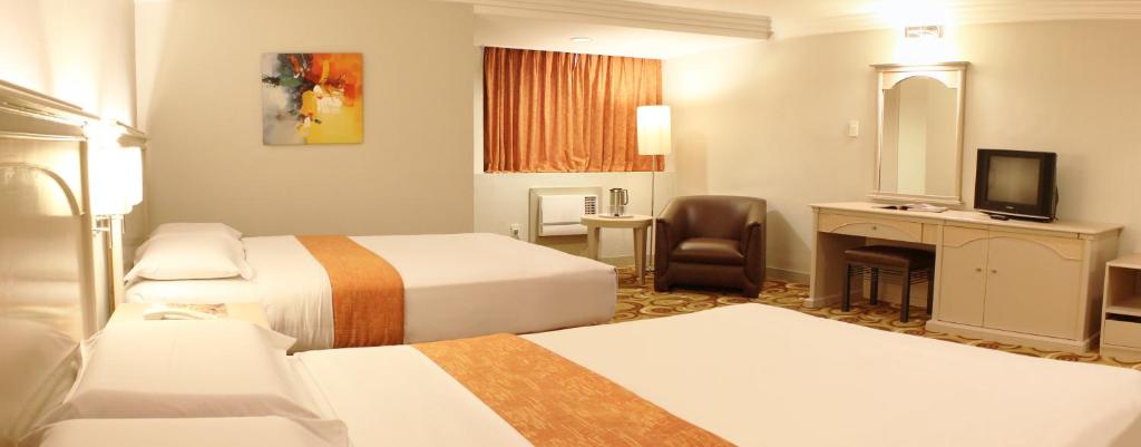 マニラにある リヴィエラ マンション ホテルのベッド2台とテレビが備わるホテルルームです。