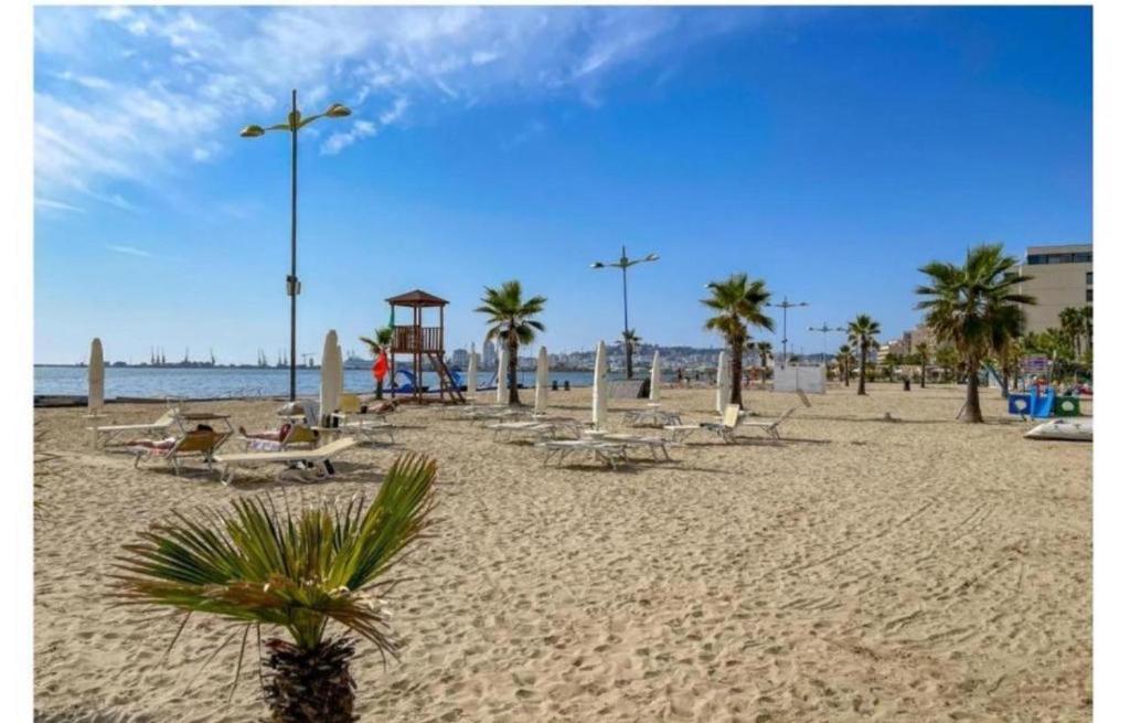 - une plage avec un bouquet de chaises et de palmiers dans l'établissement Chrigrey Holiday Apartments & Durres Beach, à Durrës