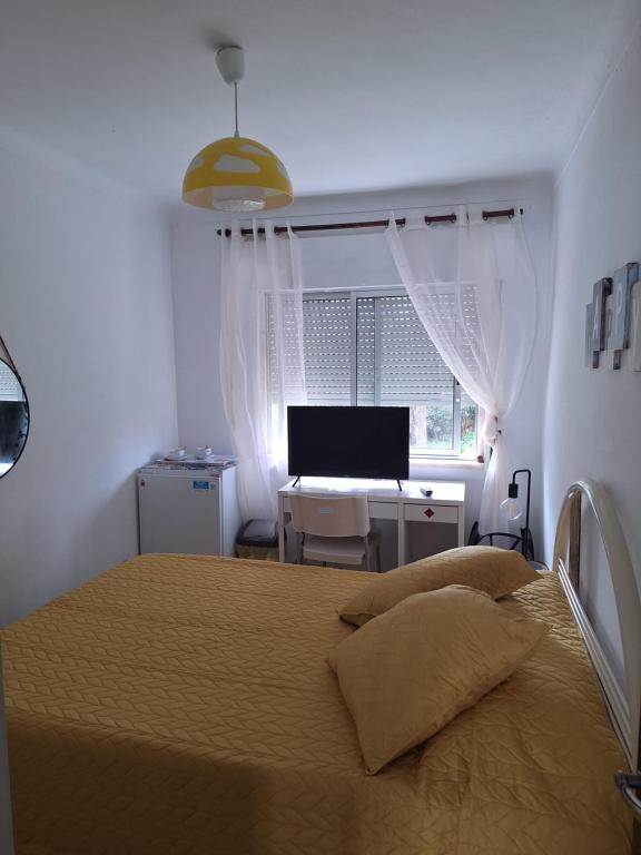 een slaapkamer met een bed en een bureau met een computer bij Quarto Salvador in Laranjeira