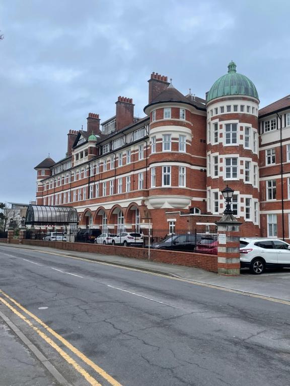 un grande edificio in mattoni rossi con macchine parcheggiate di fronte di Burlington Mansions a Bournemouth