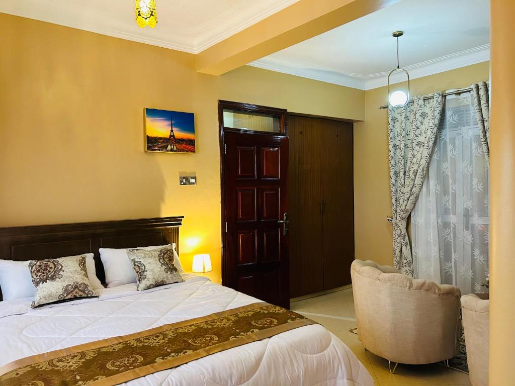 a bedroom with a bed and a chair and a window at Casa Mia BnB in Kampala