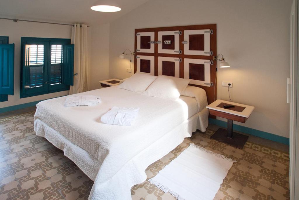 una camera da letto con un grande letto bianco con asciugamani di Hotel Hostal Chic a Sant Feliu de Guíxols