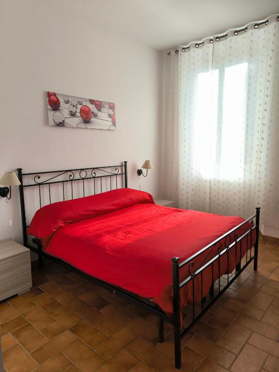 a bedroom with a bed with a red bedspread and a window at La Corte in Morlupo