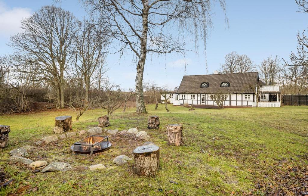 a house in a field with logs and a boat at Beautiful Home In Aakirkeby With Wifi in Åkirkeby