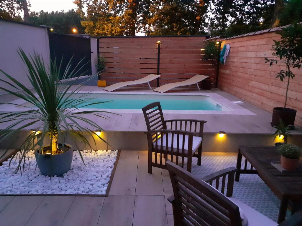 a pool with chairs and a table and a palm tree at La maison de Mona in Carcassonne