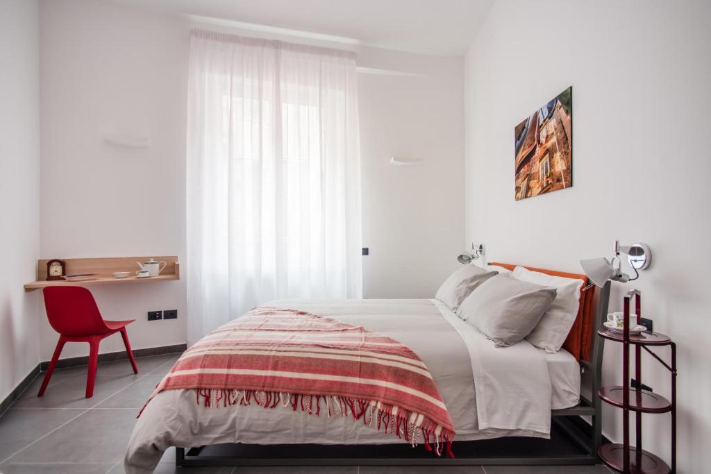 a white bedroom with a bed and a red chair at Meraki Family House in Naples