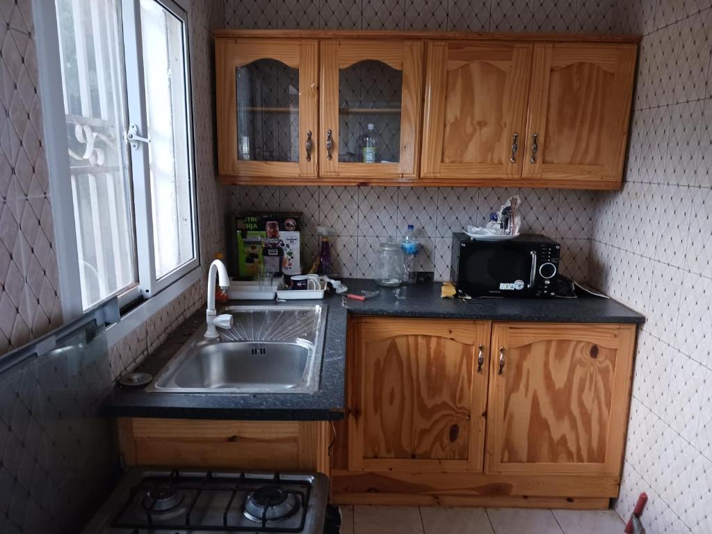 cocina con fregadero y microondas en Malikia apartment 2 Ess, en Brusubi
