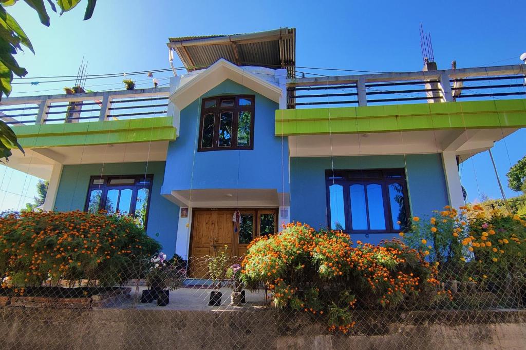 una casa azul con flores delante en Himali Homestay , Mirik, en Mirik