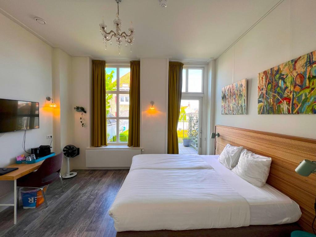 een slaapkamer met een bed, een bureau en ramen bij Hotel Loskade 45 in Middelburg