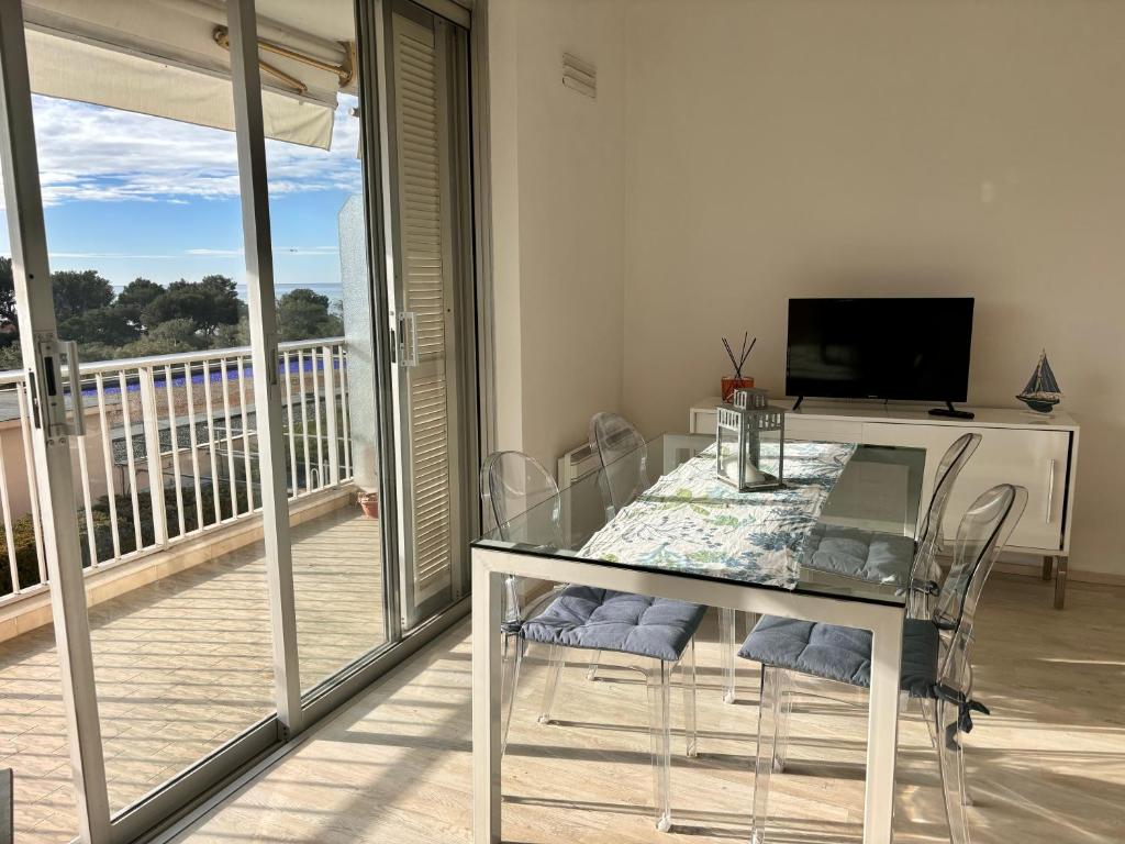 a dining room with a glass table and a balcony at French Riviera apartment with swimming pool and free parking near Monaco in Roquebrune-Cap-Martin