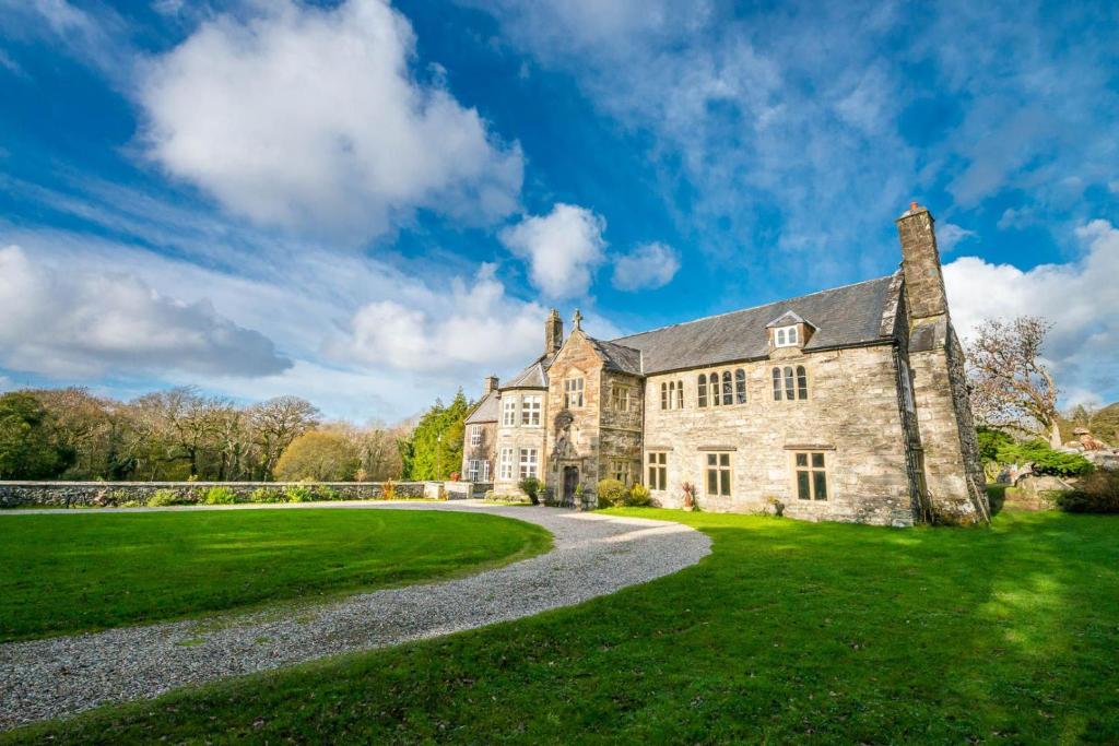 an old stone house with a gravel driveway at Gors-Y-Gedol in Dyffryn