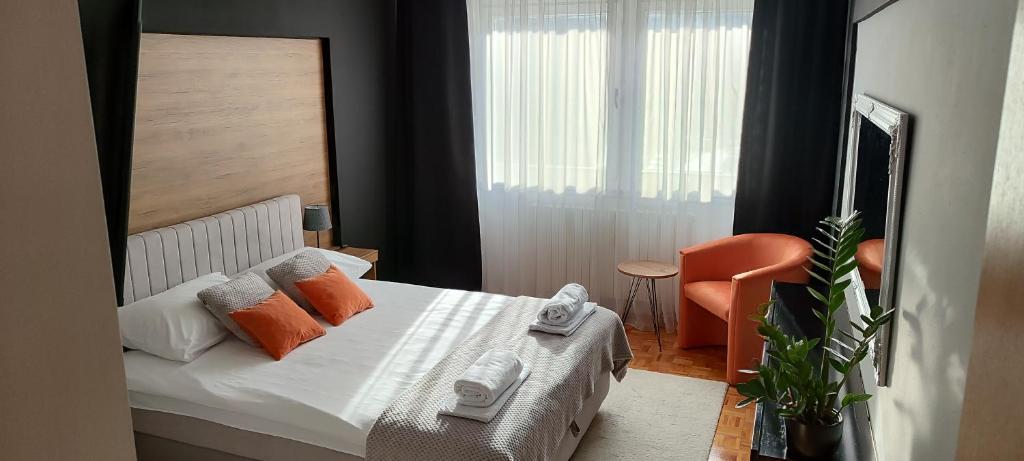 1 dormitorio con 1 cama con almohadas de color naranja y silla en Apartman Minja, en Višegrad
