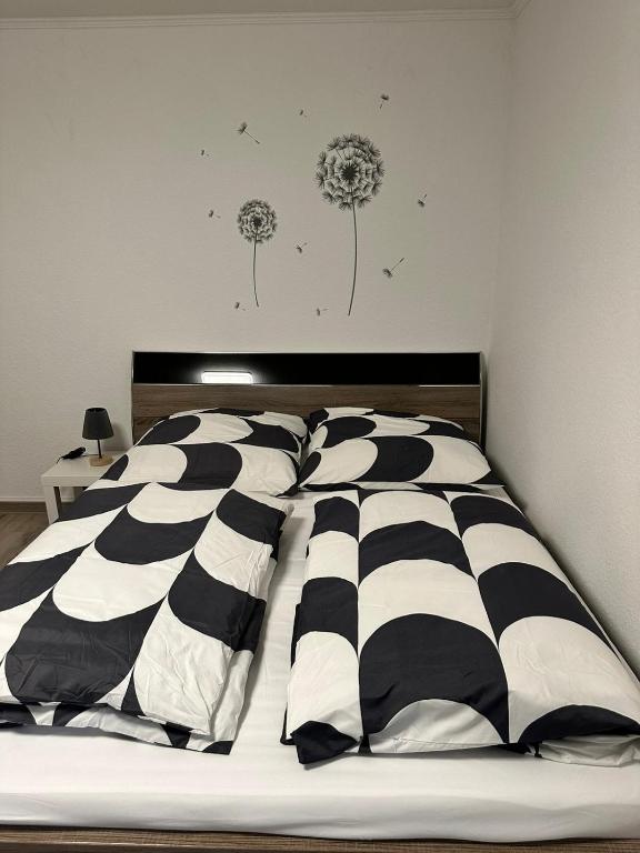 ein schwarzweißes Bett mit Löwenzahn an der Wand in der Unterkunft Schöne 2 Zimmer-Wohnung in Pulheim nah von Köln! in Pulheim