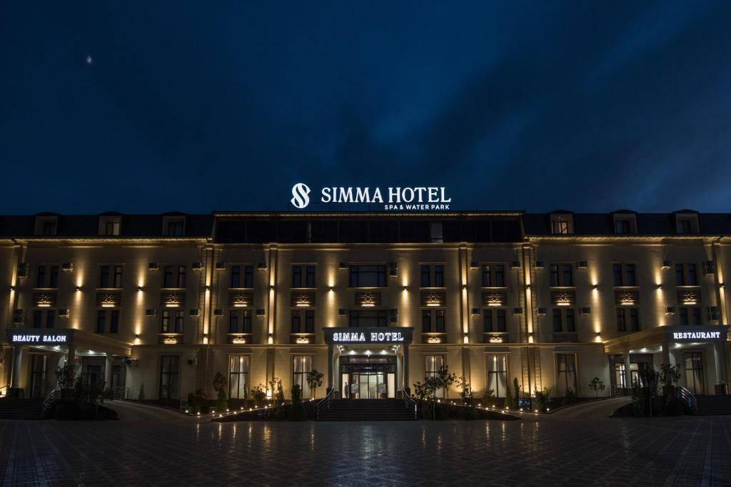 a building with a sign on top of it at night at Simma Hotel Spa & Waterpark in Tashkent