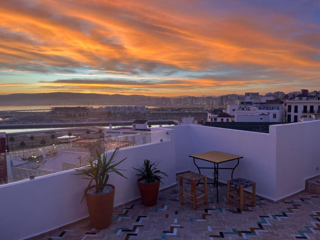 a balcony with a table and chairs at sunset at Socco Hostel in Tangier