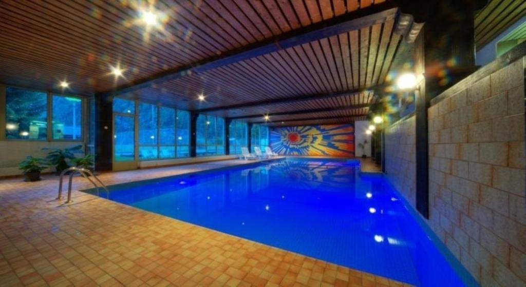 a large swimming pool with blue water in a building at Monte Rosa Täsch, Apartments mit Wellness Bereich in Täsch