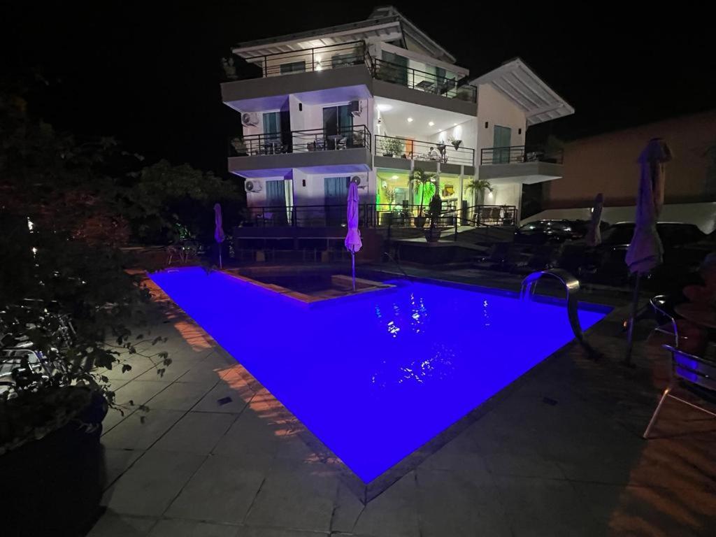 a house with a swimming pool at night at Camboinhas Beach Pousada in Niterói
