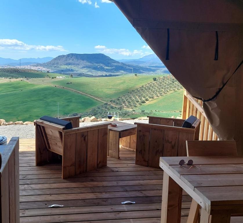 eine Terrasse mit Holztischen und -stühlen und Aussicht in der Unterkunft Glamping Vive Tus Suenos -Libertad- Caminito del Rey in Alora