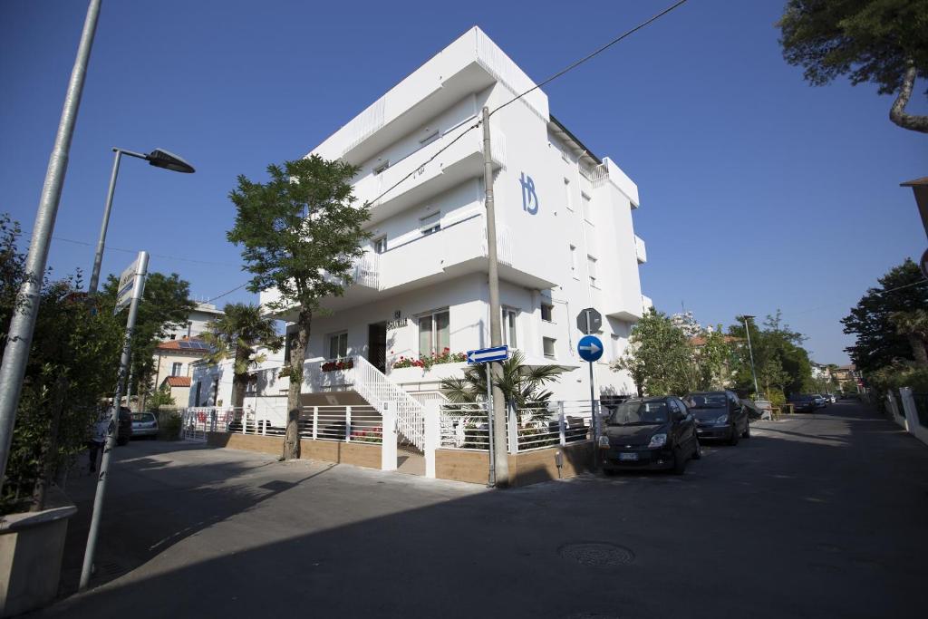 a white building with cars parked in front of it at Hotel Brunella in Rimini