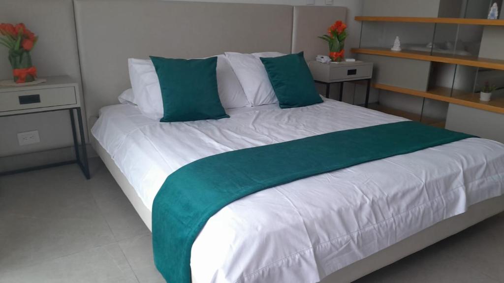 Cama con sábanas y almohadas verdes y blancas en Distrito 90, en Barranquilla