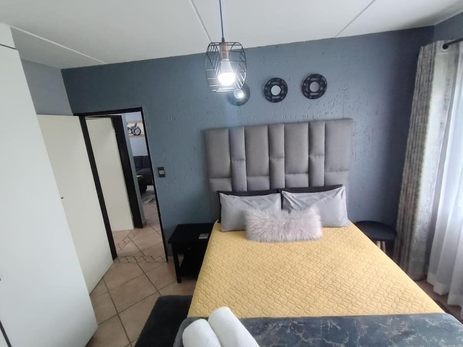 a bedroom with a yellow bed with a blue wall at Maneli 69 in Boksburg