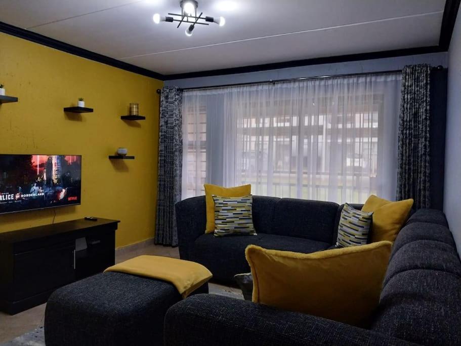 a living room with a couch and a tv at Maneli 69 in Boksburg