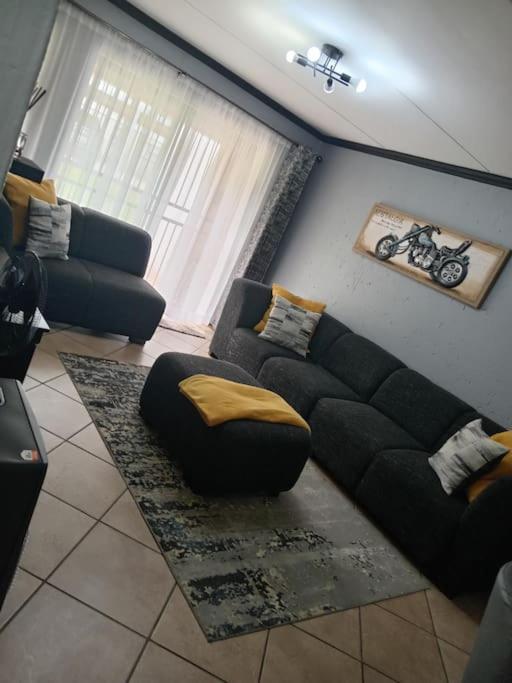 a living room with a black couch and a chair at Maneli 69 in Boksburg