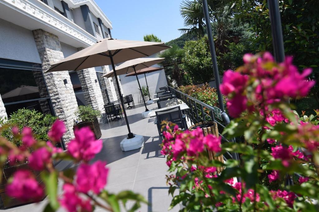 Un patio con flores rosas y una sombrilla. en Vela Verde Hotel &amp; SPA, en Yalova