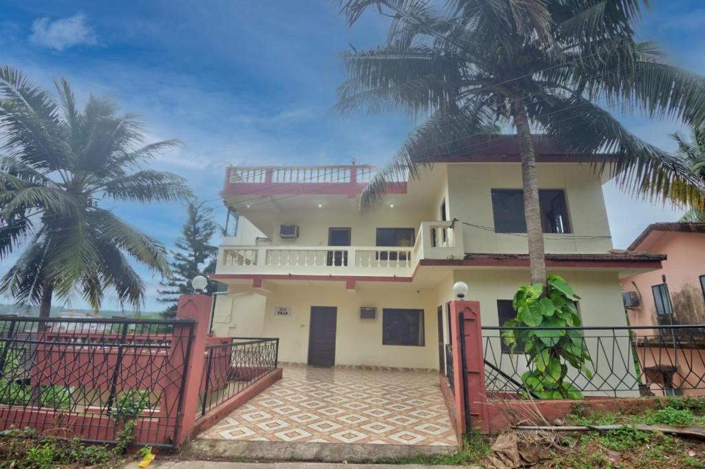 a house with a gate and a palm tree at Hilltop 3BHK Villa With Private Pool Near Candolim in Candolim
