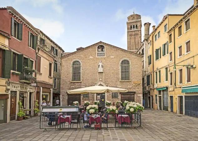una mesa con sillas y una sombrilla en una calle en Appartamento con terrazza centrale ed accogliente en Venecia