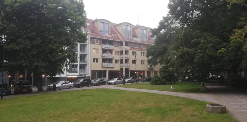 Apartament Cichy في كولوبرزيغ: عمارة سكنية كبيرة فيها سيارات متوقفة في حديقة