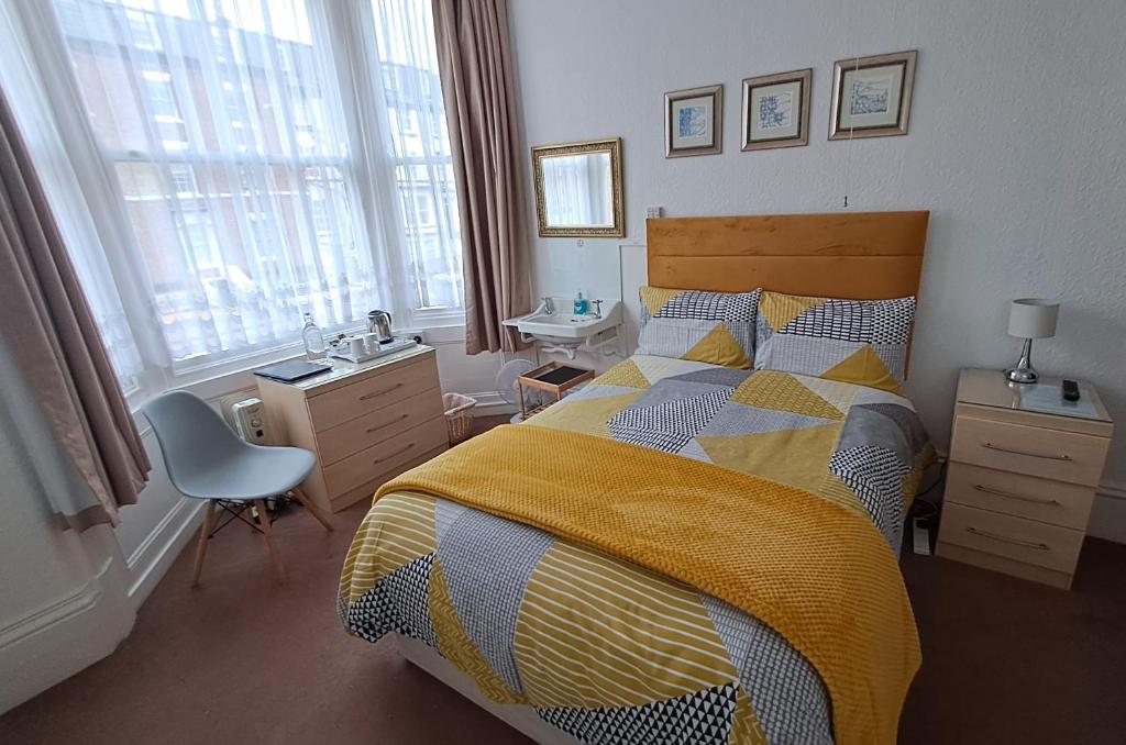 a bedroom with a bed with a yellow and blue comforter at Ainsley Court Guest House in Scarborough