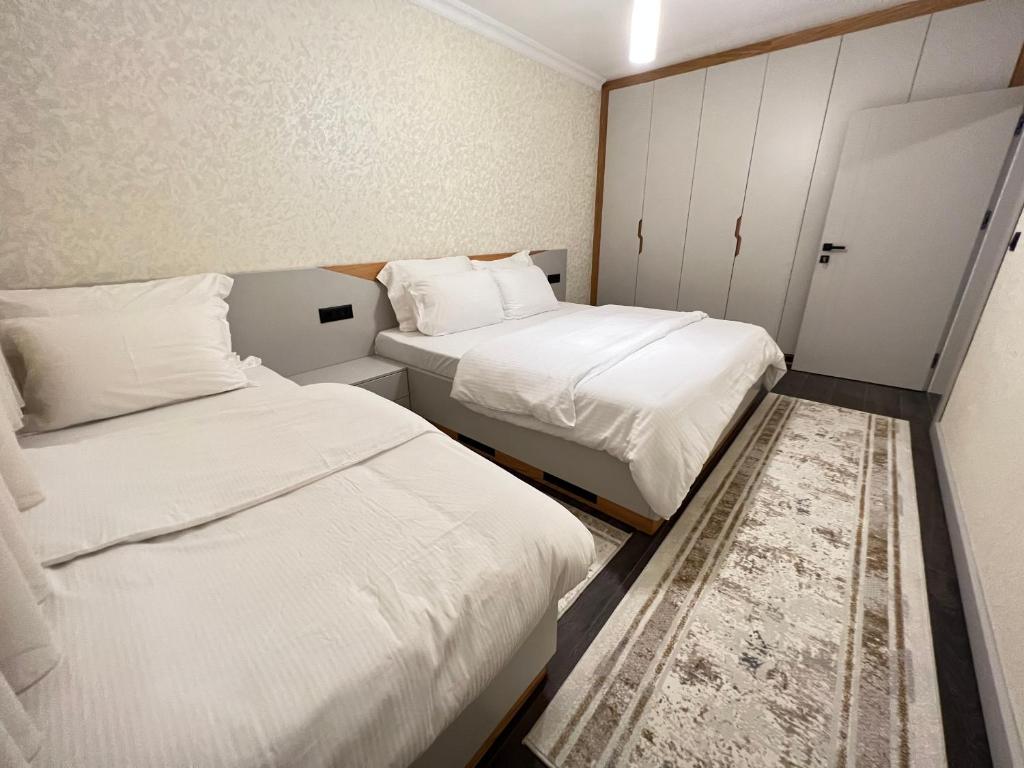 two beds in a small room with white sheets at Apartament Koha 