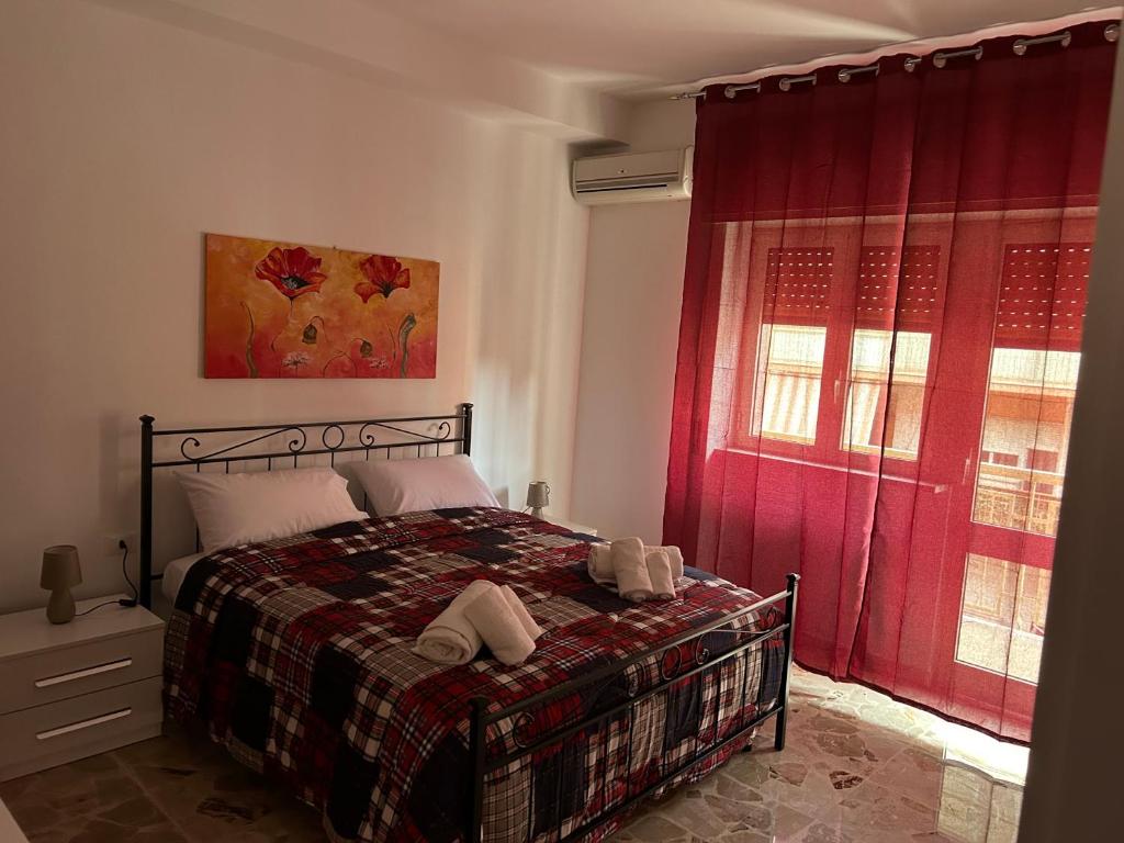 a bedroom with a bed and red curtains and a window at Luminosa casa punti cardinali in Siracusa