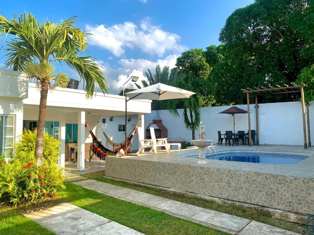 un patio trasero con piscina y una casa en Cabaña La Doña, en Santa Marta