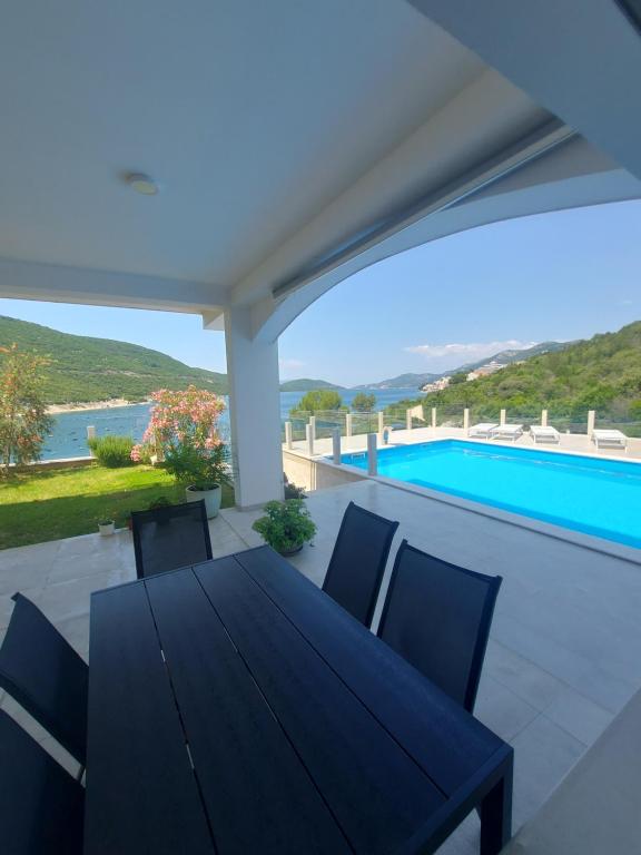 a black table and chairs on a patio with a pool at Apartmani Barka in Neum