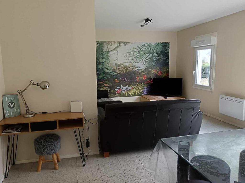 ein Wohnzimmer mit einem Schreibtisch und einem Wandgemälde in der Unterkunft MAISON 4 CHAMBRES AVEC JARDIN in Dampierre-en-Burly